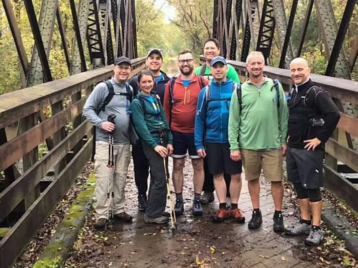 A group of 8 hikers standing on a bridge