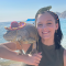 Allissa smiling on the beach while holding an iguana with a lizard on her head