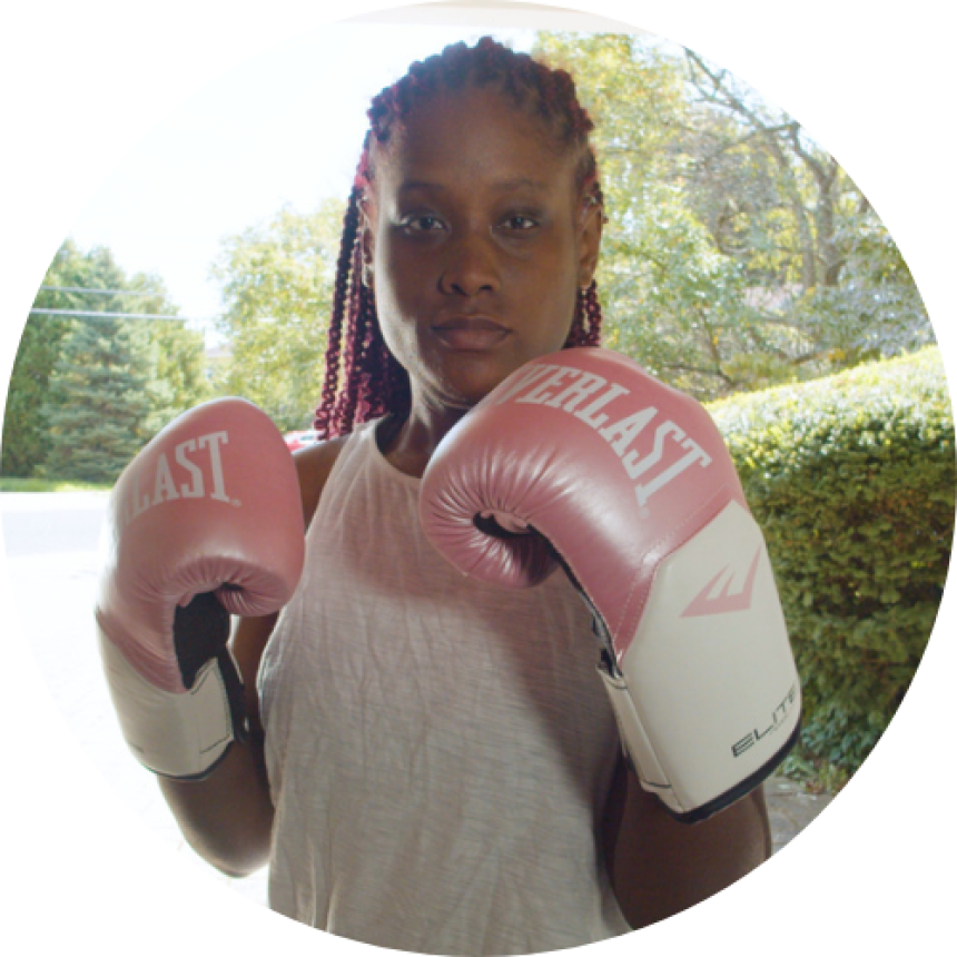 Young woman with CF, Mariah Chase, with pink boxing gloves, standing in a fighting stance