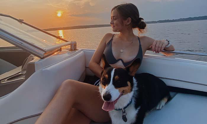 Sydney Reichart sitting on a boat with her Corgi.