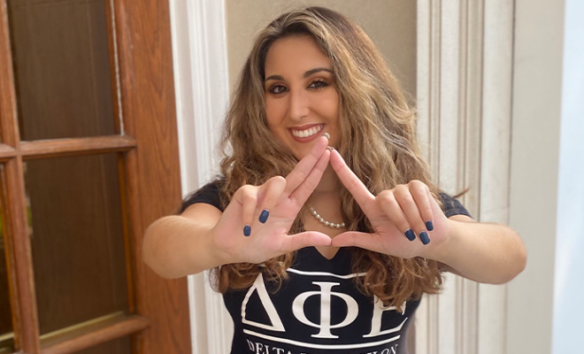 Maria Clark smiling holding up her sorority sign.