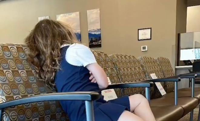 Tegan sitting in the waiting room of a doctor's office with her arms crossed.