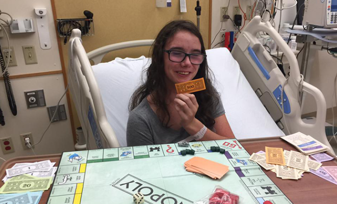 Rose playing the board game Monopoly in her hospital bed.