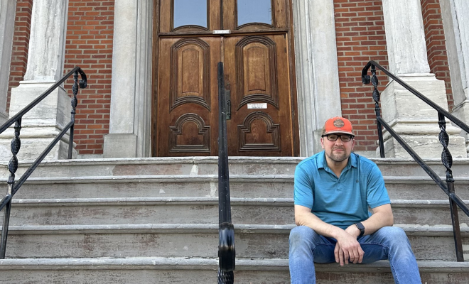 Mark Tremblay sitting on the steps of the courthouse in his childhood town.