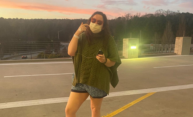 Anna Faith standing outside a hospital wearing a mask and holding her insulin pump.