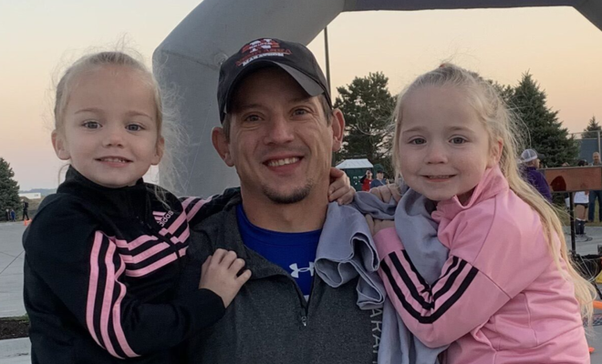 Ryan holding his two daughters at the finish line of a race